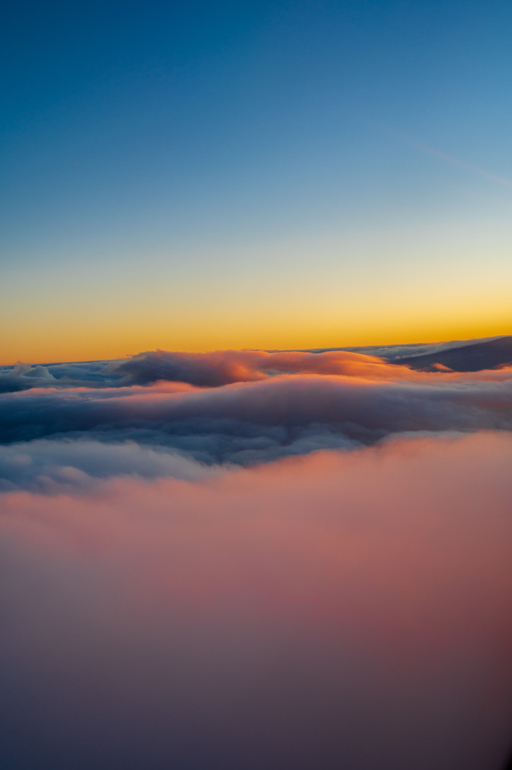 Clouds glowing pink and orange beneath a blue and gold sky