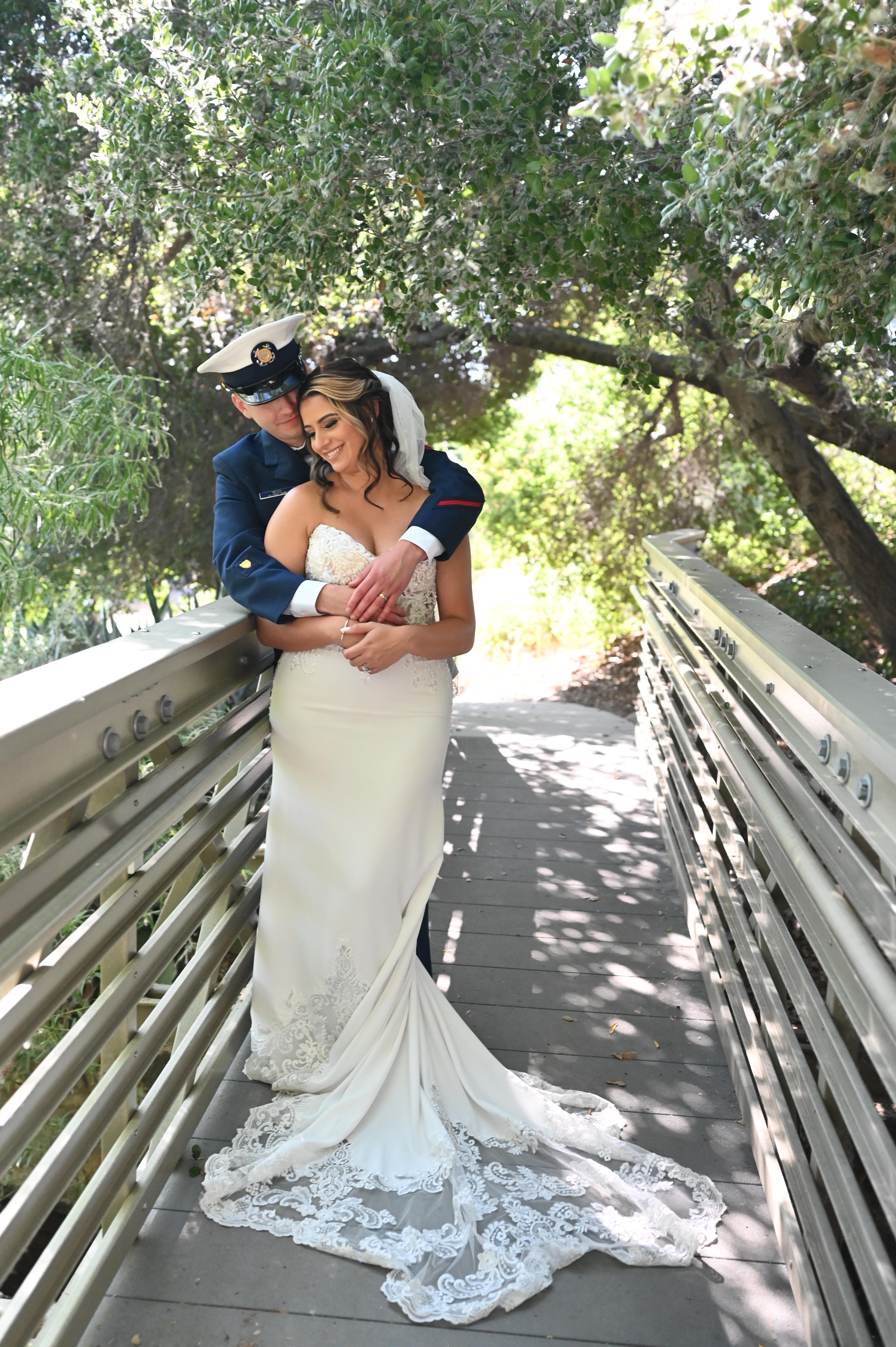 A newlywed couple embracing on a shaded garden walkway