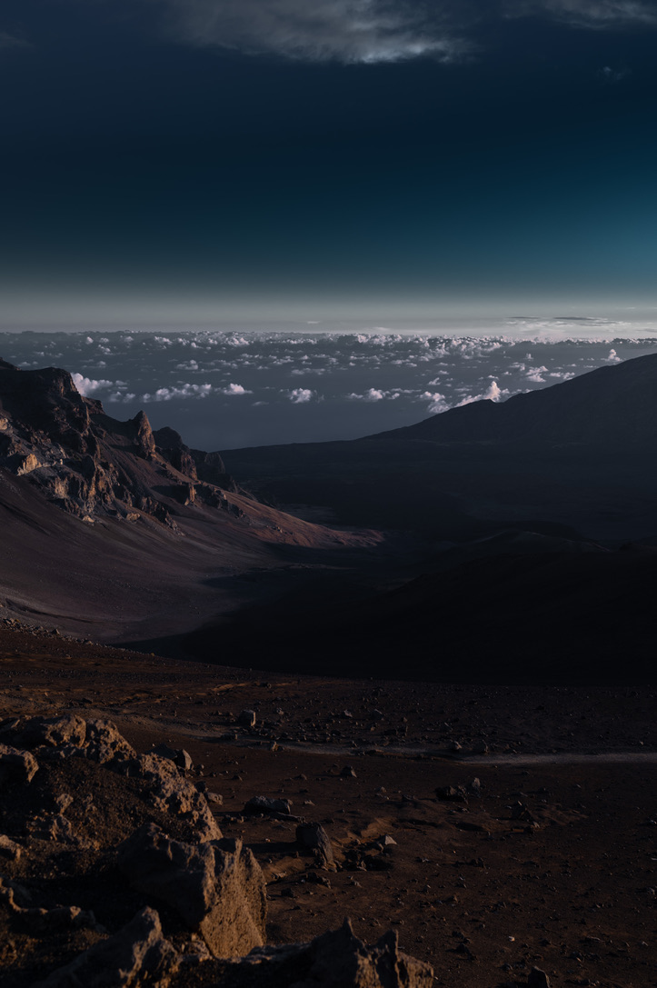 Light falling across a rugged crater with clouds on the horizon