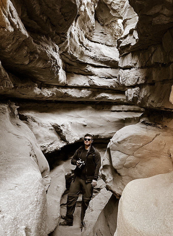 Austin Strickland holding a camera in a sculptural rock passage